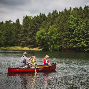 dad and two kids canoeing on lake