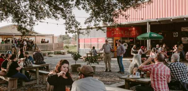 People Sitting Outside At Picnic Tables At Bayou Teche Brewing In Lafayette, LA