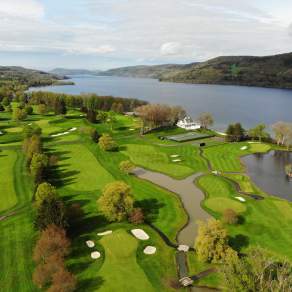 An aerial photo of a green golf course next to a body of water.