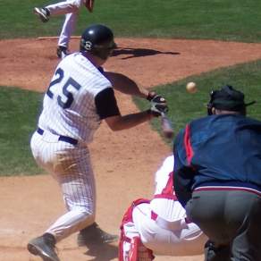 an image of a baseball player in a white uniform with the number 25 swinging his bat at a ball with an umpire and catcher behind him