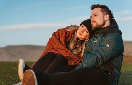 A couple (man and woman) in winter clothes watching a sunset.