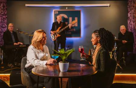Young women enjoying a drink in a bar while live musicians play on stage