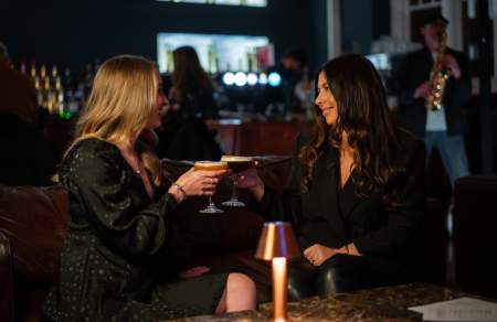 Two women sharing cocktails in a bar