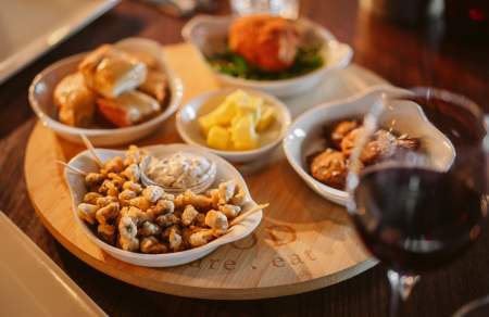 Battered cockles in a bowl with a glass of red wine.