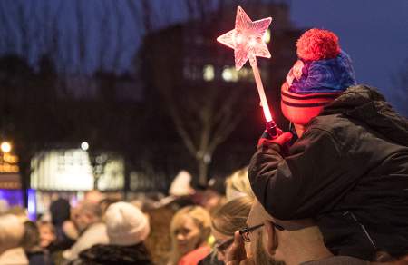 A young boy holding a star wand at the Christmas Parade