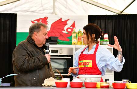 A man interviewing a woman chef in front of a Welsh flag