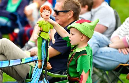 A small boy dresses as Peter Pan holding a Peter Pan doll
