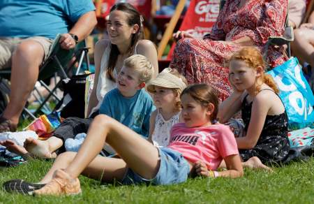 Children sitting on grass watching a show.