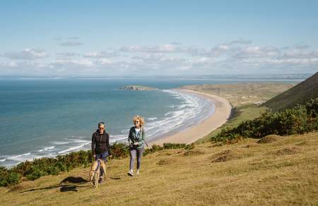 Two women walking a dog at Rhossili.