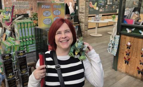 Sassy in the Butterfly Farm gift shop, she has a stuffed iguana on her shoulder smiling towards the camera