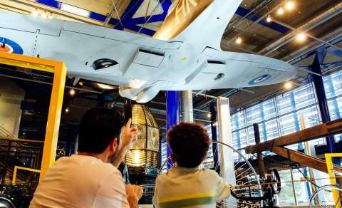 A father and son look up at the underside of a WWII plane in the ThinkTank in Birmingham