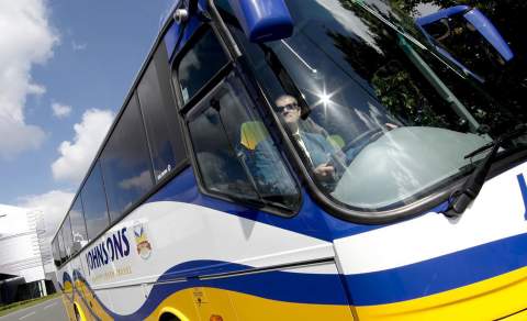 Blue white and yellow Johnsons coach driving through Birmingham