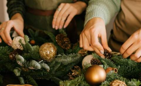 Two people making Christmas wreaths