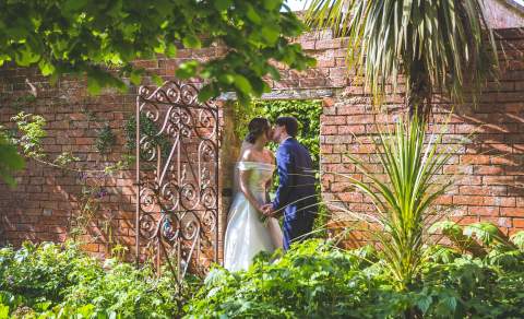 The Manor House Hotel- a couple embrace under a red brick arch way in the garden