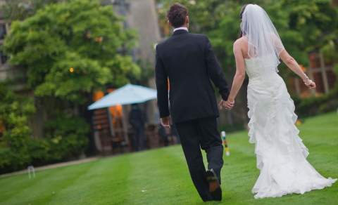 A bride and groom walk across the croquet lawn at The Greenway Hotel & Spa