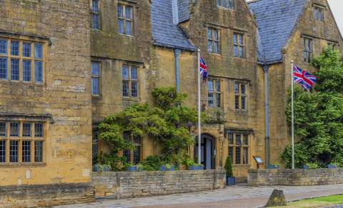 The honey-coloured Lygon Arms Hotel, in the Cotswolds, draped in wisteria with Union Jack flags flying