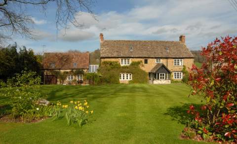 17th Century Cotswold stone farmhouse with open lawn and hedge borders