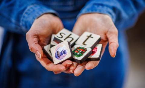 A group of wooden letter tiles are held in a person's open hands