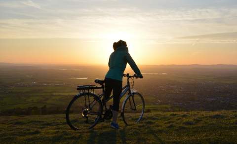 A cyclist enjoying the view of the setting sun near Cleeve Hill