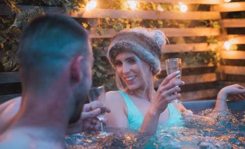 A couple enjoy a glass of wine in a hot tub at Cotswold Farm Park