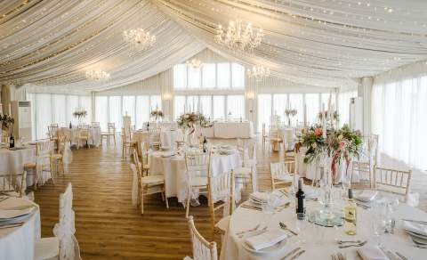 The ballroom, with chandaliers, draped ceiling and wooden floor, at the Cotswolds Hotel & Spa