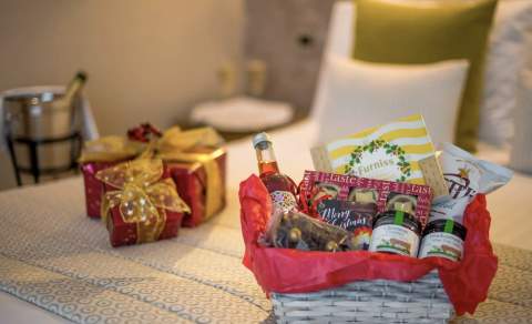 welcome basket with goodies on a bed in a hotel christmas presents in a background