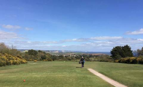 golf course and a golfer walking away sea view landscape in a disctance