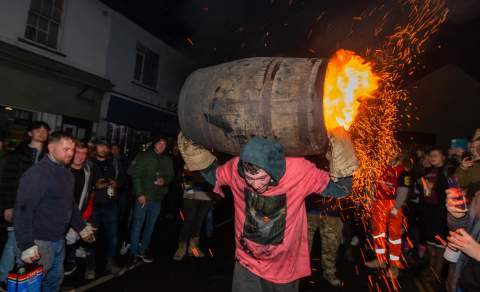 man carrying a barrel which is on fire