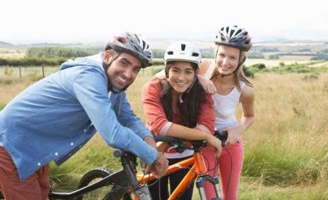three people with bikes cycling through the countryside