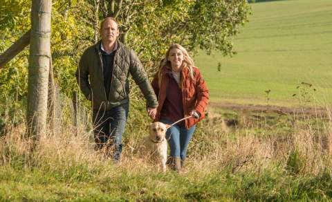 A couple walking across the Yorkshire Wolds with a dog