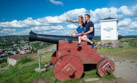 Familie som sitter på en kanon på Fredriksten festning i Halden.