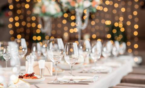 Pent dekket bord med hvit duk, glass og bokhelys