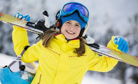 Jente i gul skijakke som holder alpintski