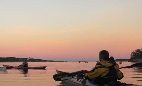Three kayaks at sea by sunset