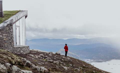 Kvinne i rød jakke ser på fjellandsskapet på Hovden.