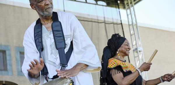 man playing a hand drum, woman shaking a sticks