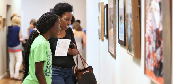 two people looking at art hanging on the wall