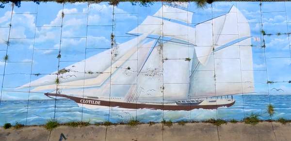 A mural painted on a concrete wall depicts the Clotilda ship