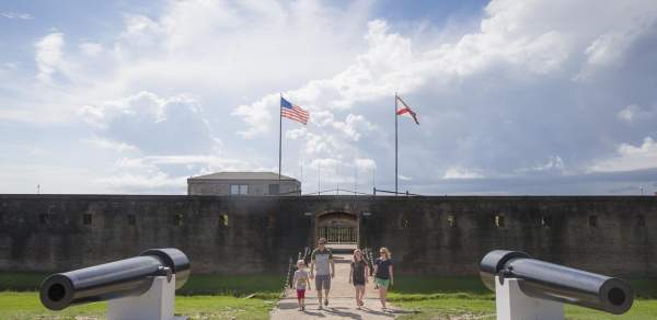 A family of four walks into Historic Fort Gaines, a brick Civil War fort guarded by black Civil War cannons