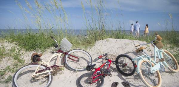 three bicycles laying on a sand dune on the beach