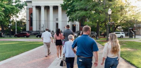 Men and women walk together on a sidewalk towards a large church
