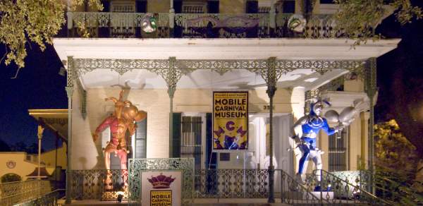 Historical, white house with iron columns and trim, two Mardi Gras Jesters on the porch