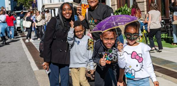 A family of five hold festive umbrellas on the street