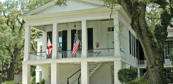 white two-story building with four columns and two flags