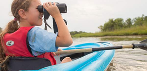 young girl in a kayak looking through binoculars
