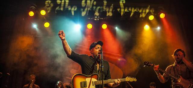 Nathaniel Rateliff sings with a guitar on a stage in Denver