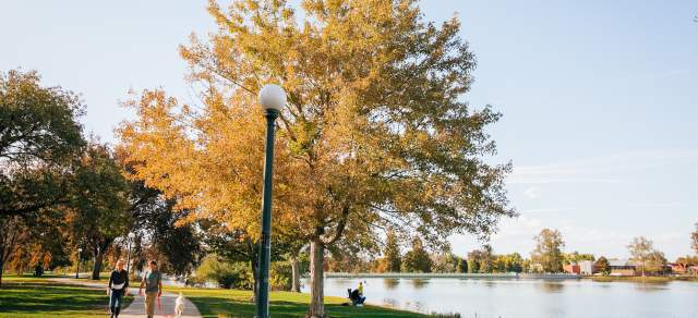 Two people walk their dog along a path at a park in Denver