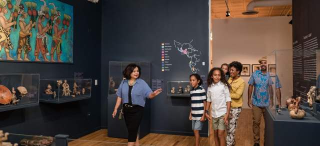 A family smiles as they walk through an exhibit at Museo de las Americas