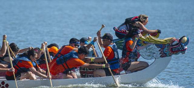 A dragon boat team paddles on a reservoir in Denver