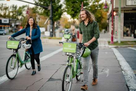 Two people walking GREENbike's around the 9th and 9th location of Salt Lake.